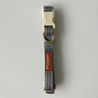Dog collar with blue plaid pattern and brown leather patch on a gray background