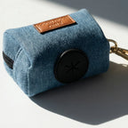 Blue denim dog waste bag holder with  gold keychain on a light gray background