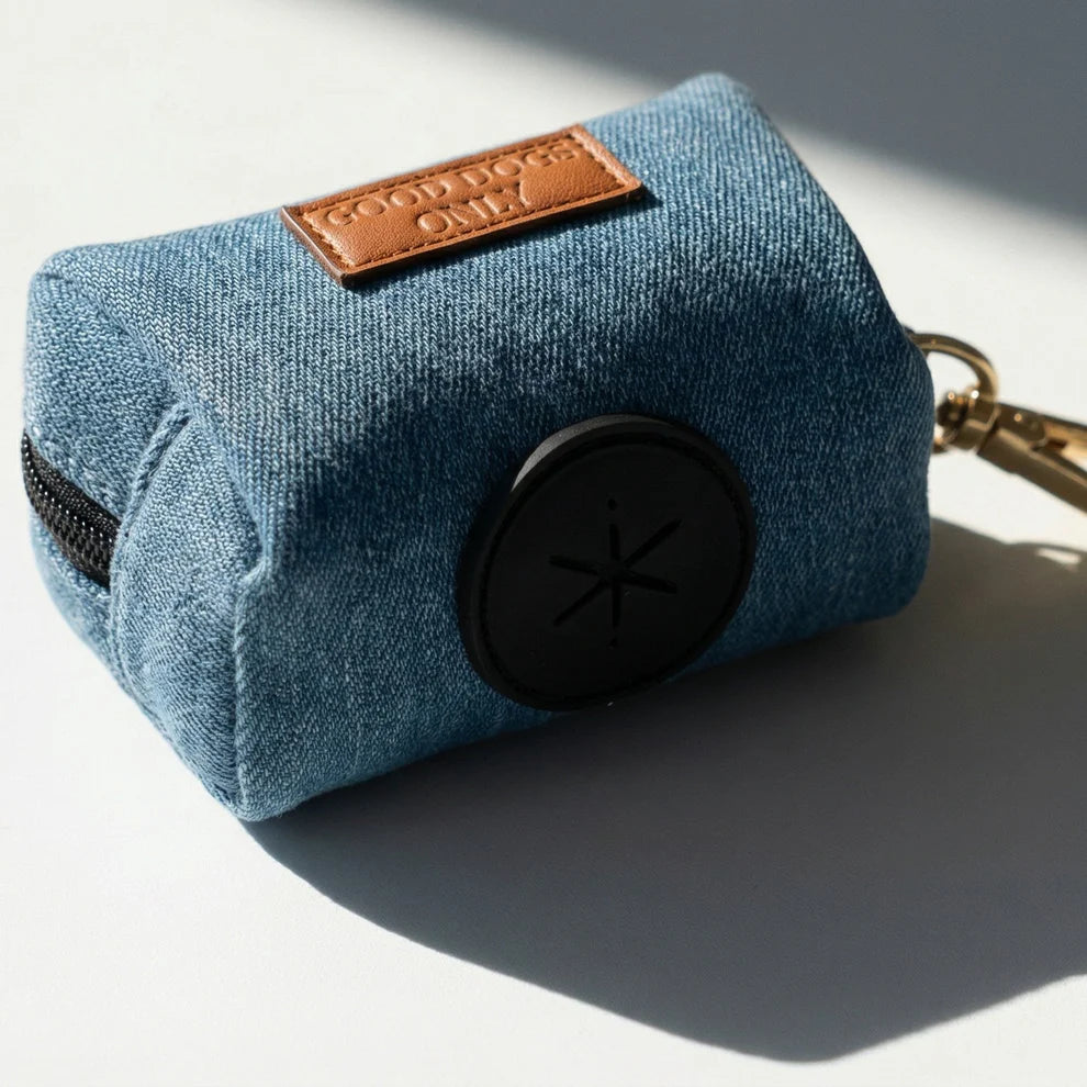 Blue denim dog waste bag holder with  gold keychain on a light gray background