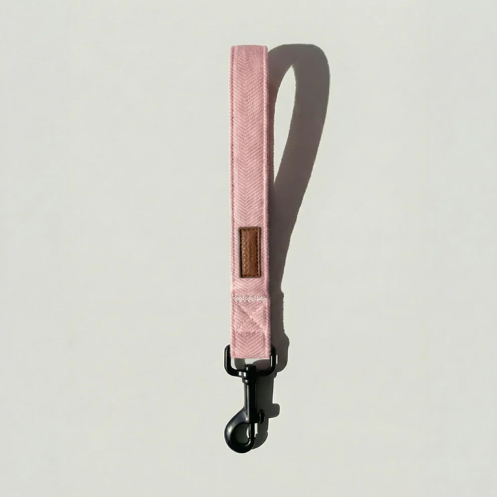 Pink dog leash with a black clip on a light gray background