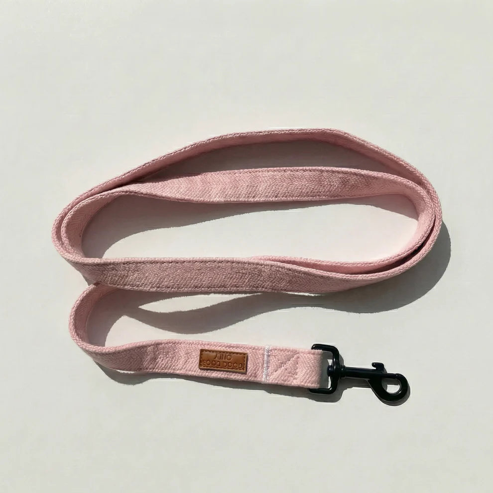 Pink dog leash with a brown leather patch on a light gray background