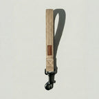 Beige dog leash with a brown patch on a light gray background