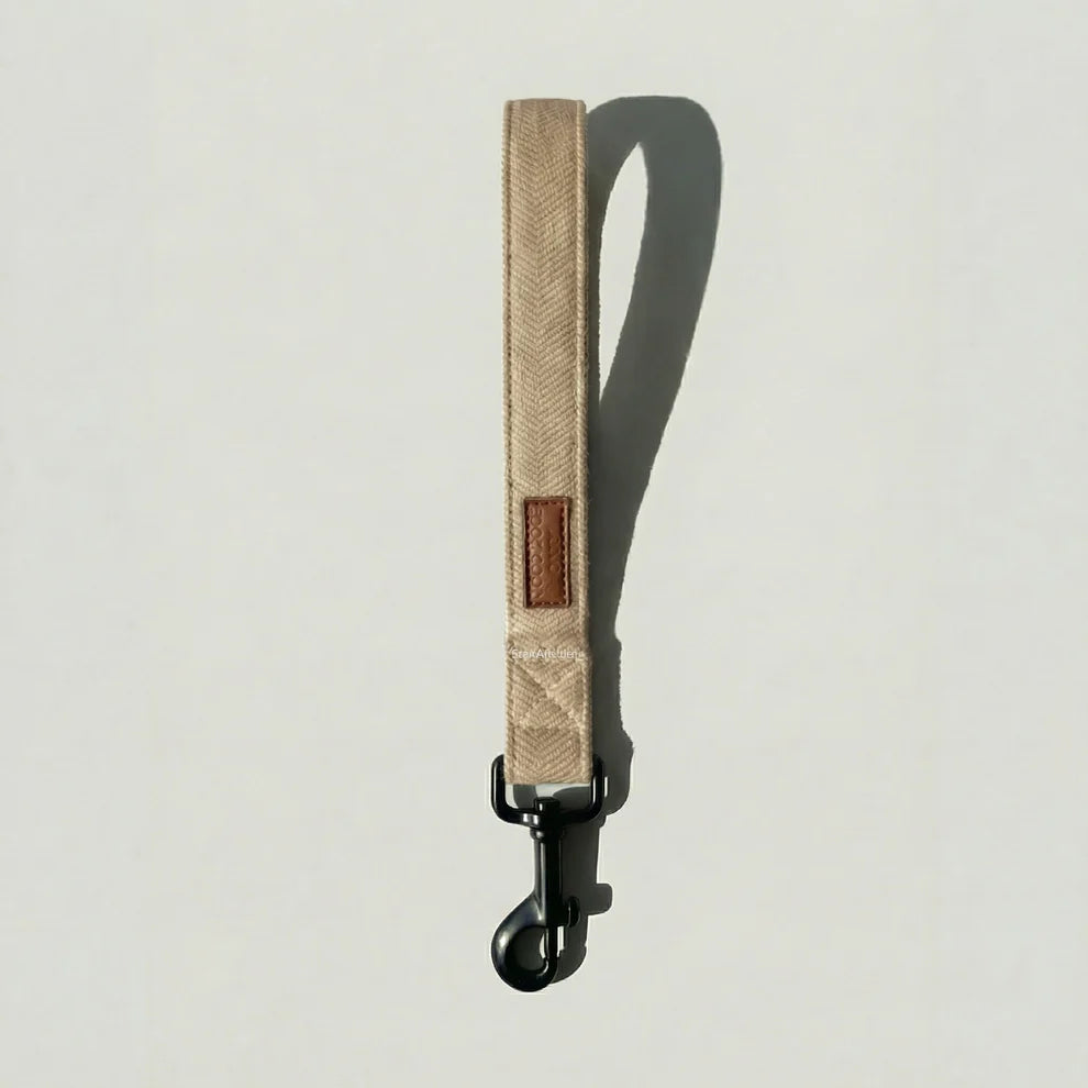 Beige dog leash with a brown patch on a light gray background