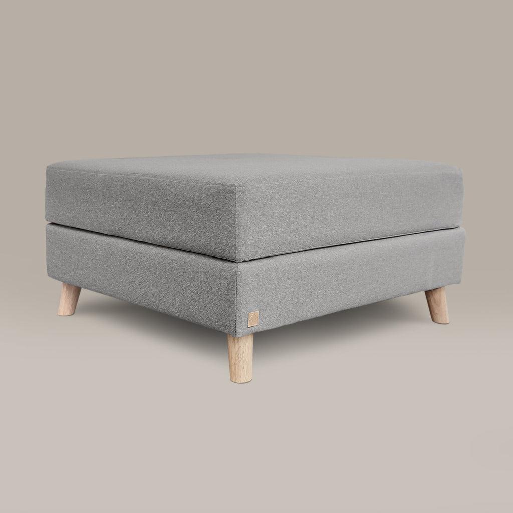 Gray upholstered ottoman with wooden legs on a beige background