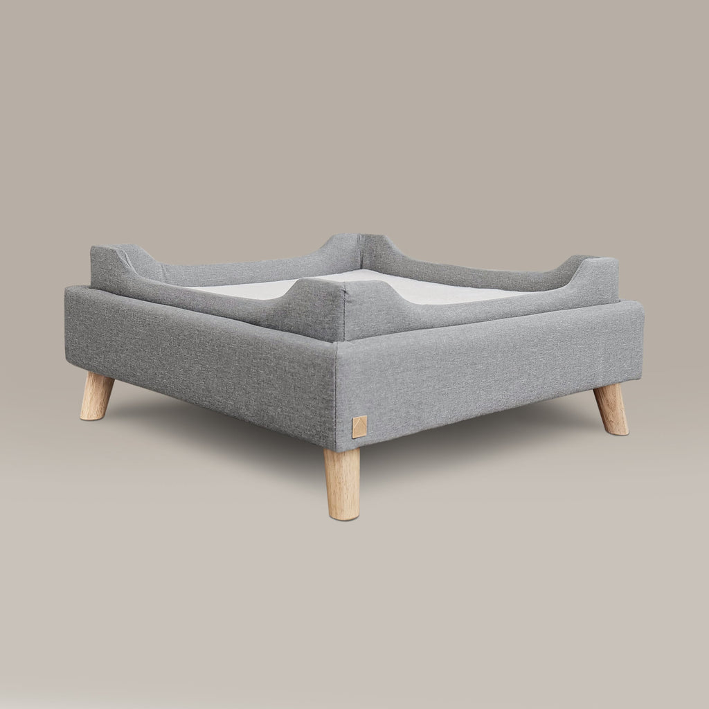 Gray pet bed with wooden legs on a beige background