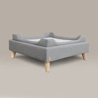 Gray pet bed with wooden legs on a beige background