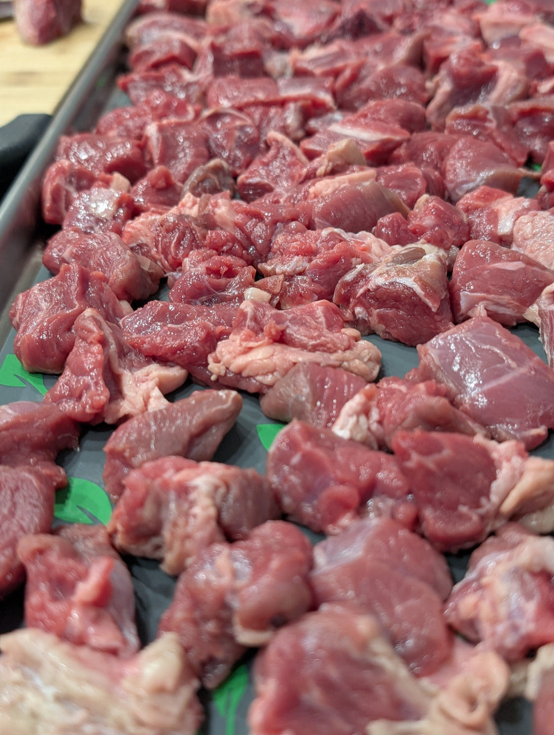 Raw diced meat on a black tray