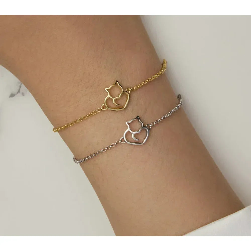 Two cat-shaped bracelet charms on a wrist against a neutral background