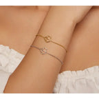 Two gold and silver cat-shaped bracelets on a person's wrist against a neutral background.