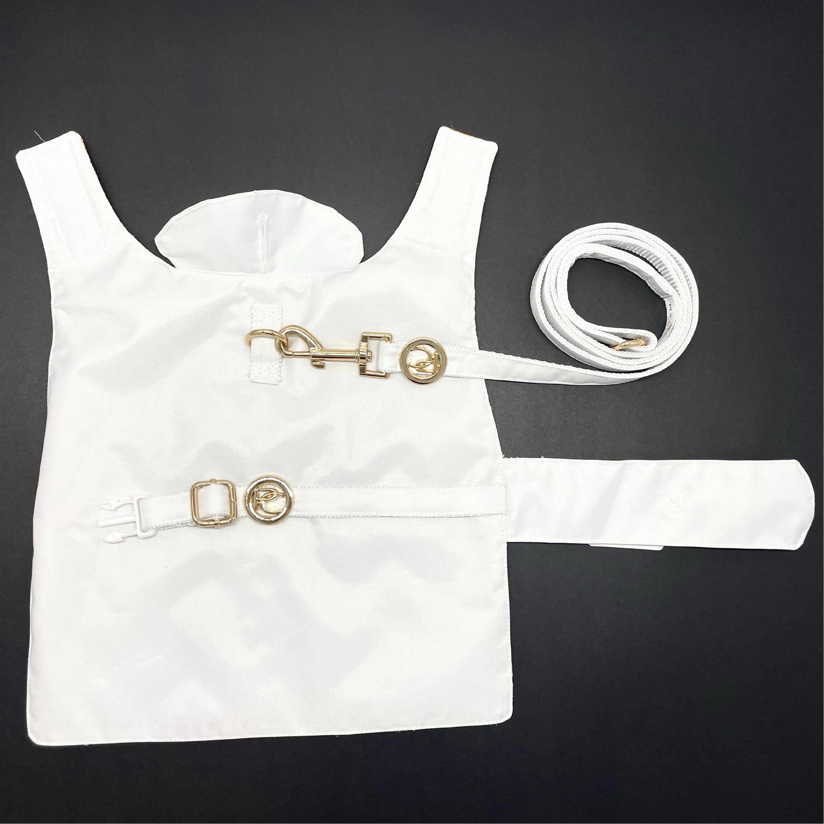 White dog raincoat with gold accents on a black background